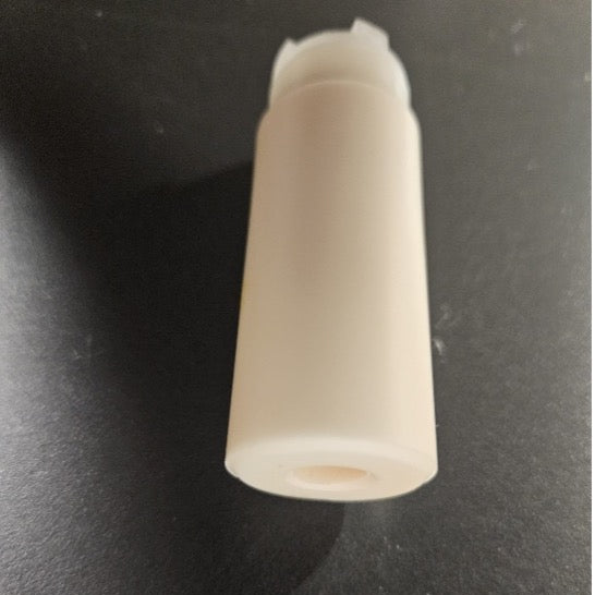 A small off-white plastic cylindrical component with a threaded top, photographed on a dark textured surface.
