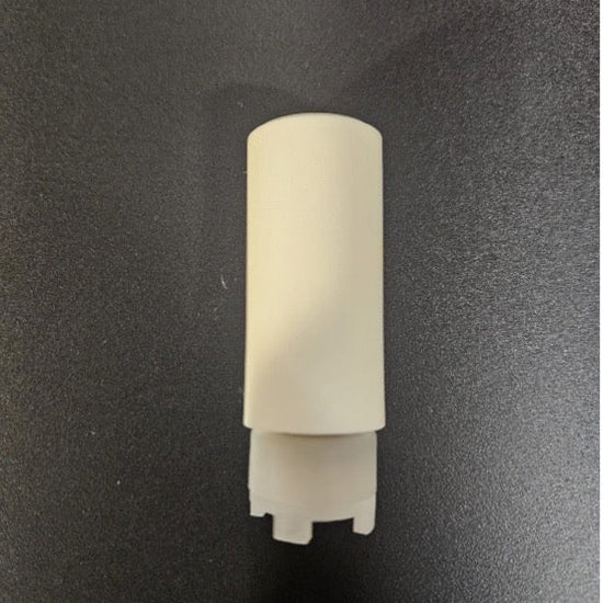 A small off-white plastic cylindrical component with a flared base, photographed upright on a dark textured surface.