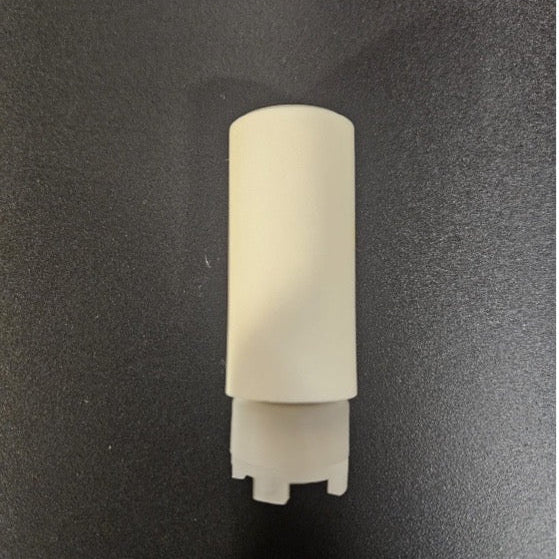 A small off-white plastic cylindrical component with a flared base, photographed upright on a dark textured surface.